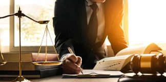 Lawyer writing at desk with scales and gavel