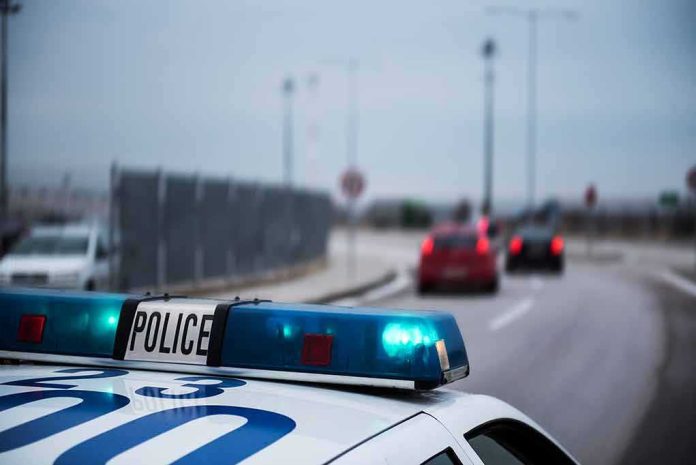 shutterstock_1030980538 Police car with blue lights on near a roadway