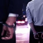 Ex-Candidate Tied To Hollywood Bloodbath Two men in handcuffs with police lights in the background