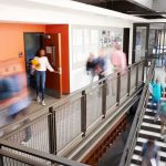 Students walking through a modern school hallway and stairwell