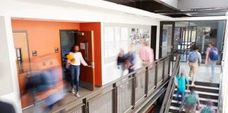 Trump’s Trans Crackdown- Slams Public Schools Students walking through a modern school hallway and stairwell