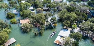 Midwest Towns Drown Overnight Aerial view of flooded neighborhood with rescue boat navigating streets