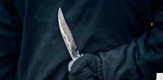 Blood-On-Blade Text Shocks Judge Gloved hand holding a serrated knife against a dark jacket