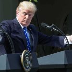 Iran TV Targets Barron — $10M Bounty? man at podiums with arms outstretched during outdoor press event