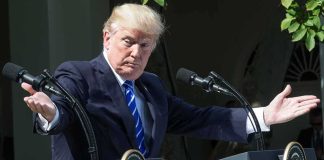 man at podiums with arms outstretched during outdoor press event