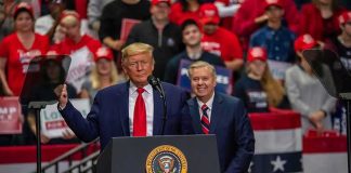 two men at a podium during a large indoor rally