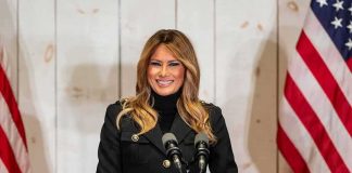 Melania’s Quiet Dealings Rattle Moscow woman speaking at podium with microphones and US flags