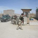 Armed soldiers patrol near a guard post outside a walled compound