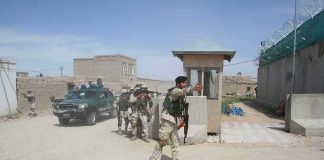 Armed soldiers patrol near a guard post outside a walled compound