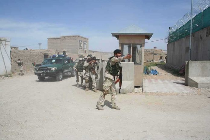 shutterstock_1931171399 Armed soldiers patrol near a guard post outside a walled compound