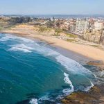 Kamala Harris New Home Raises 2028 Questions Aerial view of a coastal city beach with waves and rocky shoreline