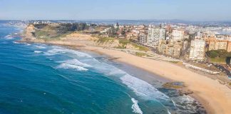 Kamala Harris New Home Raises 2028 Questions Aerial view of a coastal city beach with waves and rocky shoreline