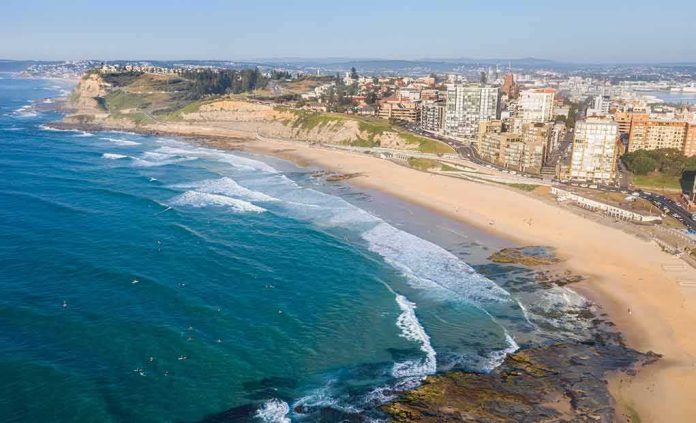shutterstock_2066671334 Aerial view of a coastal city beach with waves and rocky shoreline