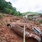 Glacier Collapse Triggers Himalayan Carnage Landslide debris covering houses and a buried car on a muddy hillside