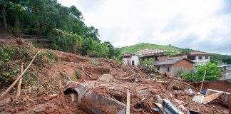 Glacier Collapse Triggers Himalayan Carnage Landslide debris covering houses and a buried car on a muddy hillside