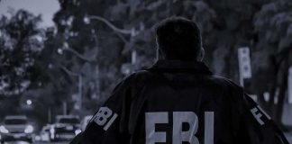 FBI agent in jacket facing a city street at dusk