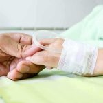 Brain-Eating Amoeba Teen Critically ill A person holding the hand of a patient with an IV in a hospital bed