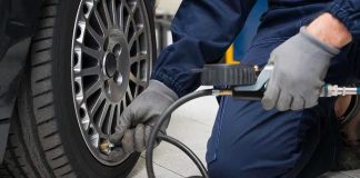 Mechanic inflating a car tire in a workshop