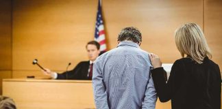 Trusted Recruiter Exploits Recruits — Bank Chaos Defendant in handcuffs stands before a judge in a courtroom
