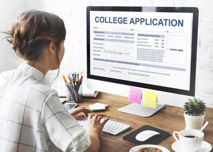 Student completing a college application on a desktop computer