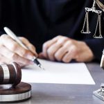 Mental Health Twist For Arrested Potential Trump Assassin Judge writing at desk with gavel and Lady Justice statue