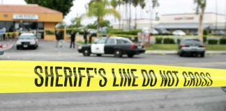 yellow sheriff's line tape blocks a street near police cars