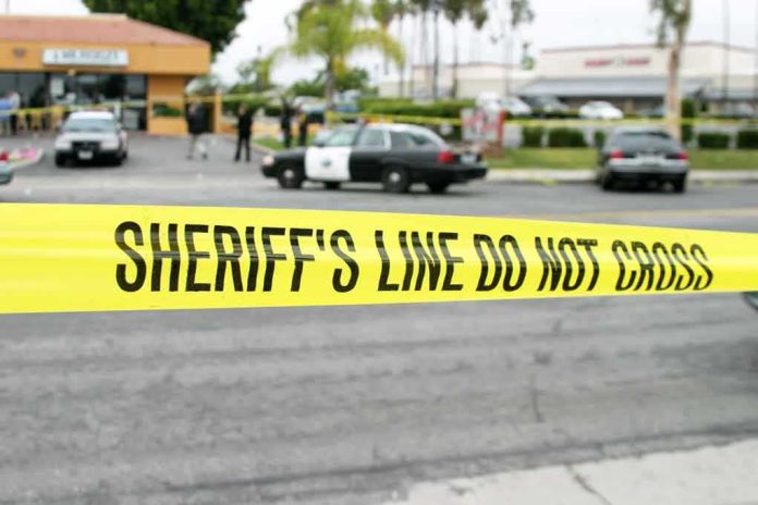 shutterstock_79306801 yellow sheriff's line tape blocks a street near police cars