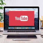 YouTube logo on a laptop screen on desk.