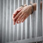 Judge’s Stunning Leniency Ignites Fury handcuffed hands resting through prison bars