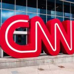 Press Pass Purge – Court Showdown Looms CNN red logo sculpture outside a modern glass building