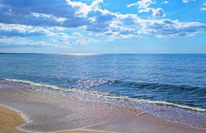 shutterstock_1141328969 Sandy beach with gentle waves under a bright blue sky