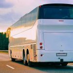 I-95 Carnage Sparks English-Only Crackdown White coach bus driving on a highway at sunset