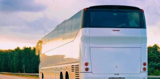 White coach bus driving on a highway at sunset
