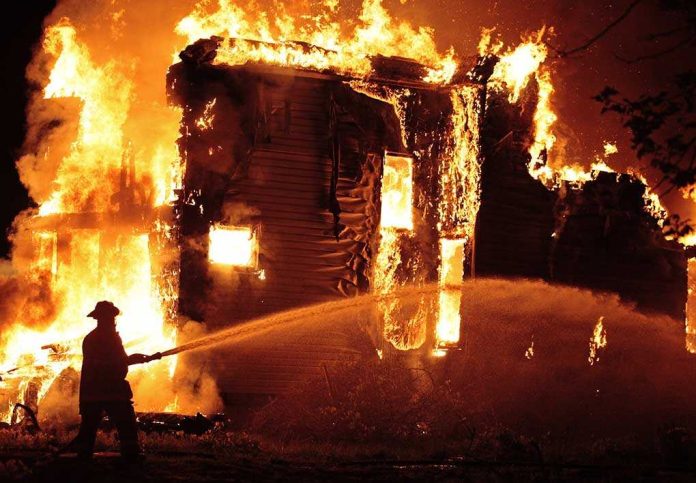 shutterstock_143200255 A firefighter battling a large house fire at night