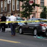 Holiday Melee: Cop Dragged, Guns Seized Police at urban street crime scene with yellow tape around parked cars
