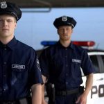 Two police officers standing near a patrol car