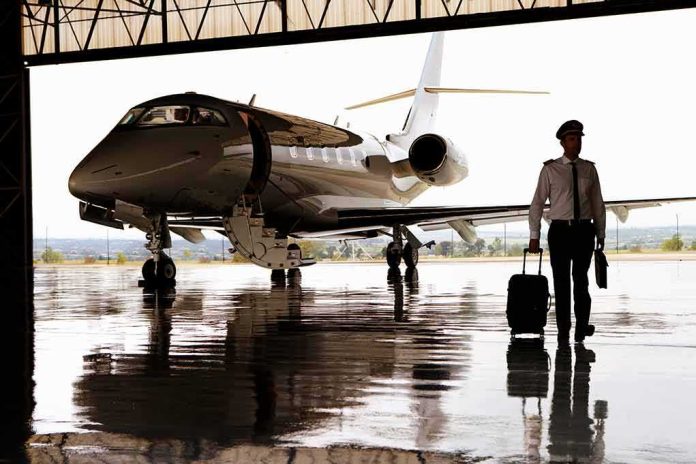 Pilot walking with suitcase beside private jet in hangar