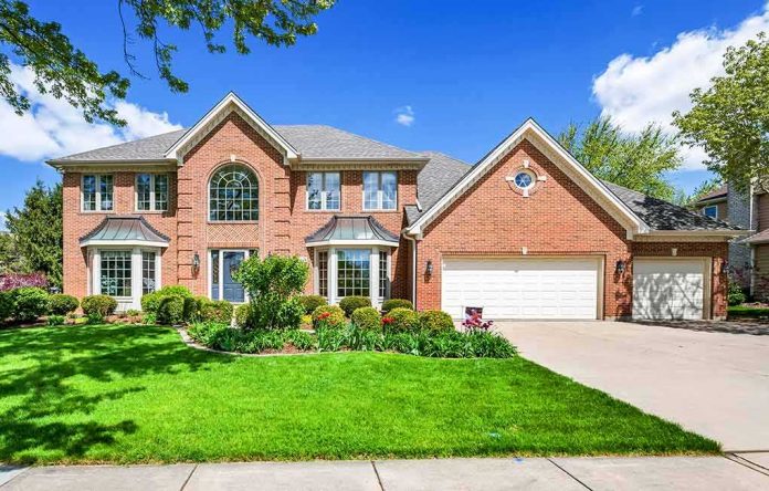 shutterstock_1701991546 Brick suburban house with two-story facade and three-car garage