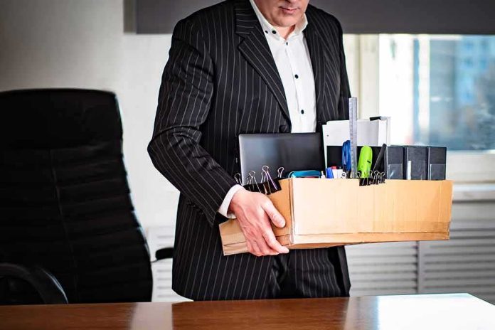 shutterstock_1704289006 Office worker in suit carrying a box of personal items
