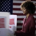 Power Shift Looms In New Hampshire Voter at a polling booth with an American flag backdrop