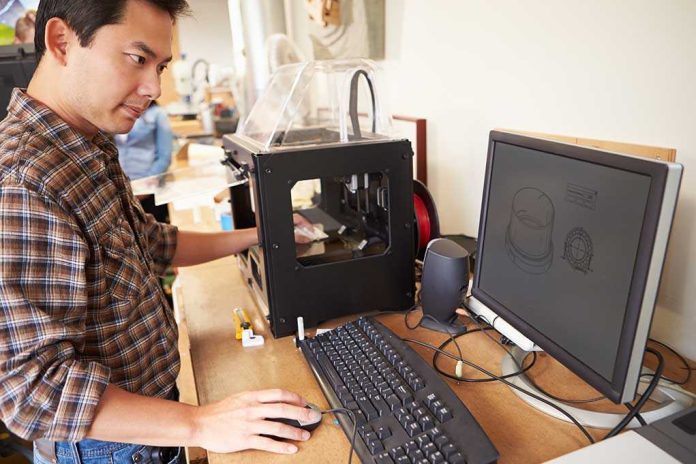 shutterstock_184664579 Man operating a 3D printer next to a computer with CAD designs