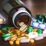 Assorted pills and capsules spilling from a brown bottle