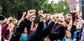 Crowd of protesters with raised fists wearing masks