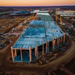 Trump’s $15B Steel Bombshell aerial view of large industrial building under construction at sunset
