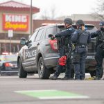 Custody Papers Left Beside Bodies Police officers gather beside a patrol SUV at a taped-off scene
