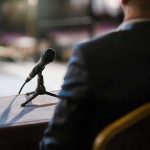 Microphone on a table near a seated person in a suit