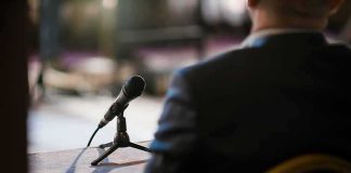 Microphone on a table near a seated person in a suit