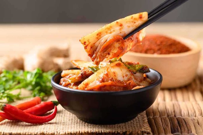 Chopsticks lifting kimchi from a black bowl