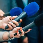 Epstein Island Drop Sparks Chilling Questions Reporters holding colorful microphones