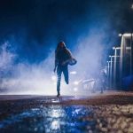Person running at night near police car with flashing lights